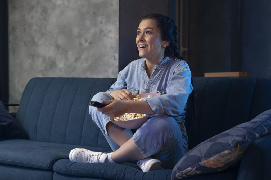 Dia do Solteiro: dicas para aproveitar seu dia com estilo Mulher assistindo série no sofá